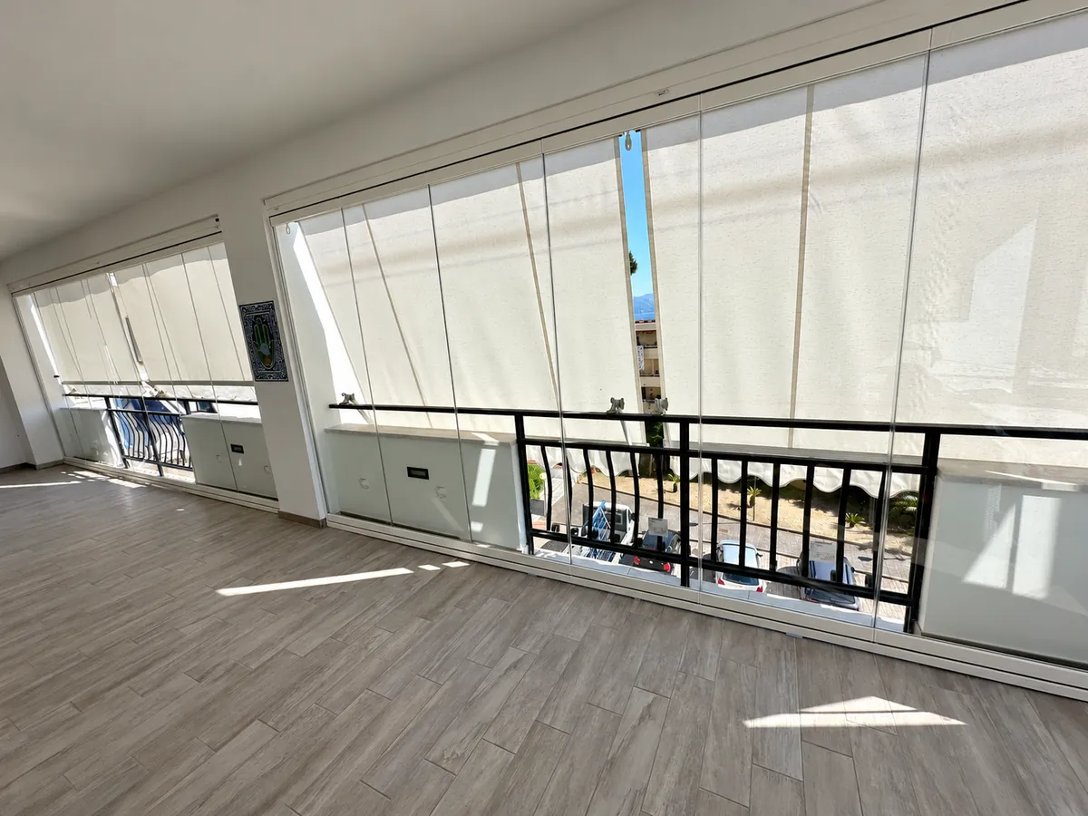 Vetrate su un balcone con ringhiera nera e tende esterne abbassate.