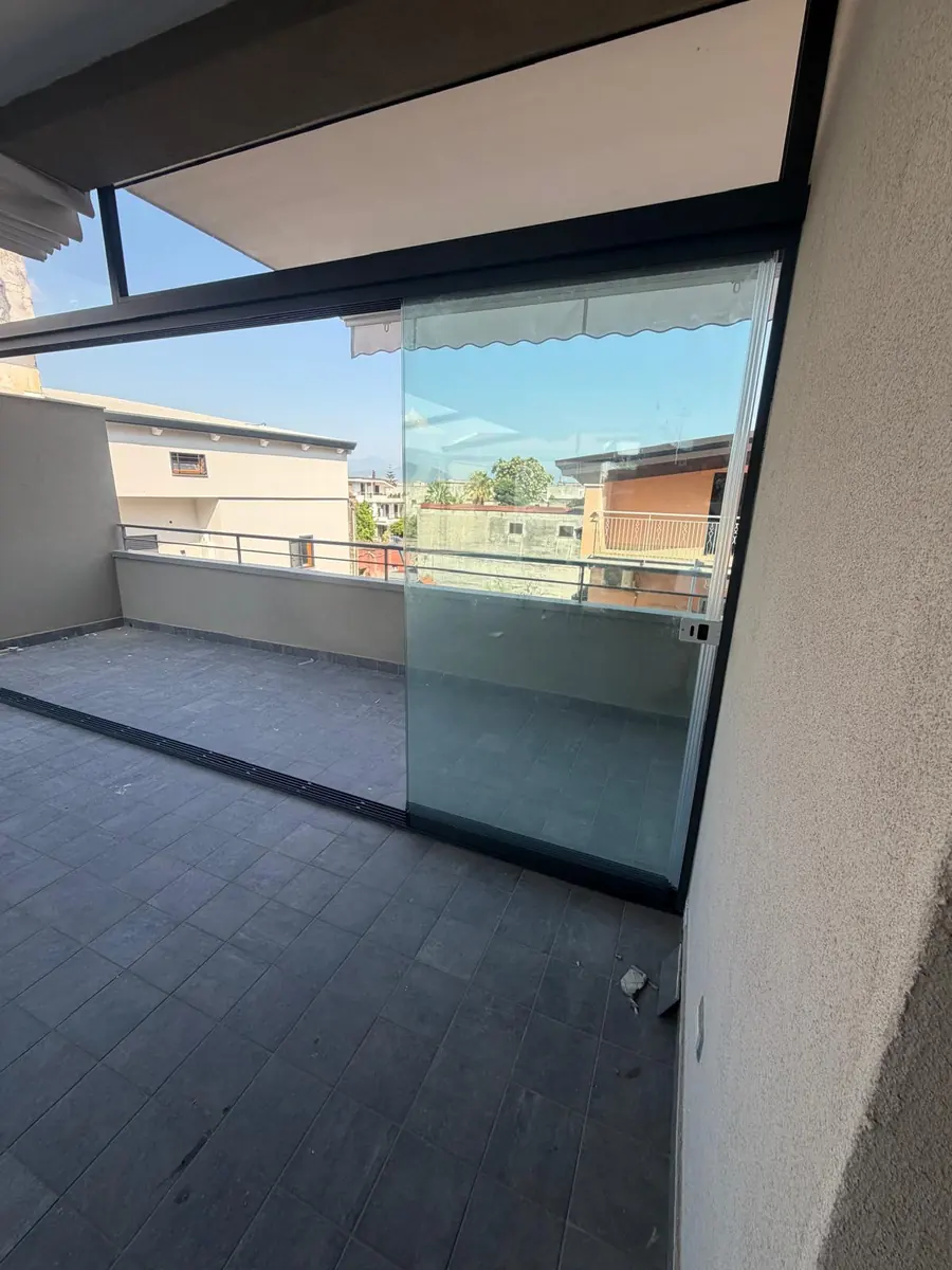 Vetrate panoramiche con profili scuri e parapetto lungo un terrazzo.